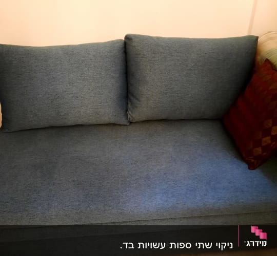 ספה כחולה עם כריות על רצפת עץ